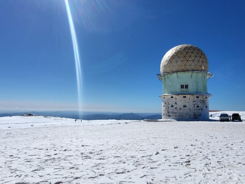 Snowy landscape and radar tower at Serra da Estrela mountains in Portugal under a bright blue sky